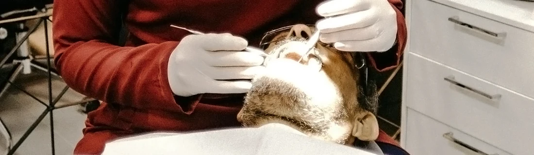 Dentist Lewiston ME Dental Crowns Focused A dental patient is lying back in a chair with a bright light on his face while the dentist works on his mouth