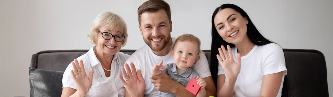 Dentist Lewiston ME Family Dentistry Focused happy family is sat on a couch waving at the camera