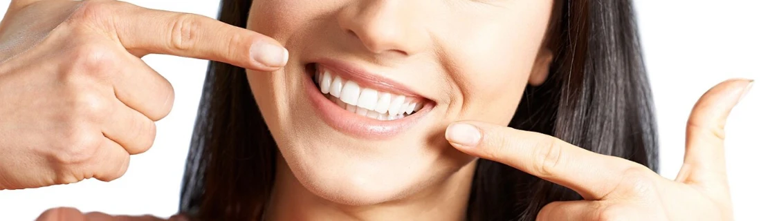 Dentist Lewiston ME Gum Grafting Contouring Woman smiling wide and pointing at her teeth