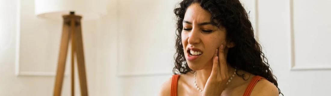 Dentist Lewiston ME Tooth Jaw Pain woman with long dark hair holding her hand up to her jaw as if in pain